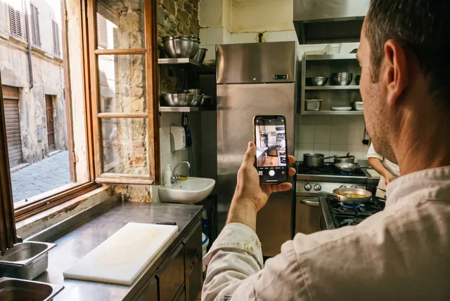 Un cuoco fotografa la cucina con lo smartphone